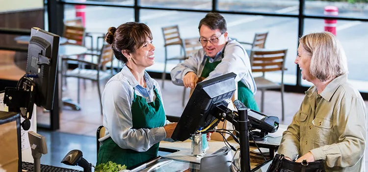 Two grocery store employees checking out a customer.