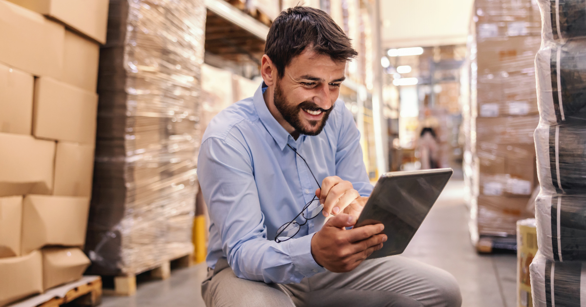 B2B merchant in a warehouse using a tablet to manage payments and transactions, representing faster funding and improved visibility with commercial card acceptance.