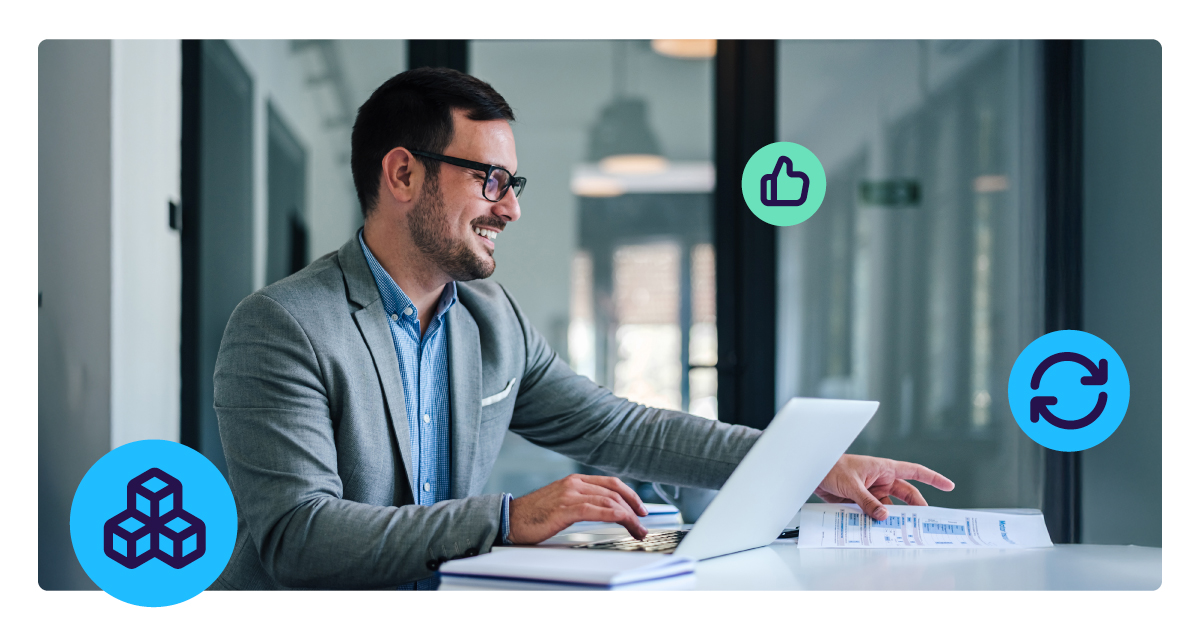Man sits at computer, smiling whilst looking at his screen.