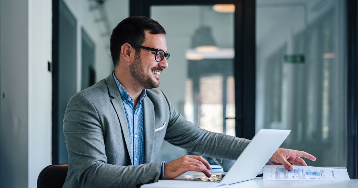 Man sits at computer with smile on his face knowing how to use his CRM in a banking environment.