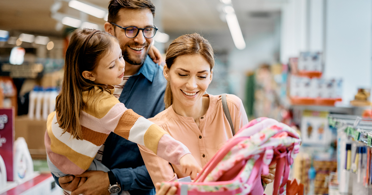 Millennial parents look at a jumper in a store. The man has a young child in his arms
