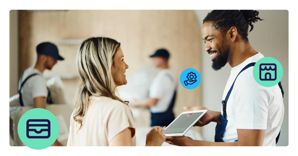 A decorator smiles as he hands over his ipad to allow the customer to pay. She smiles back.