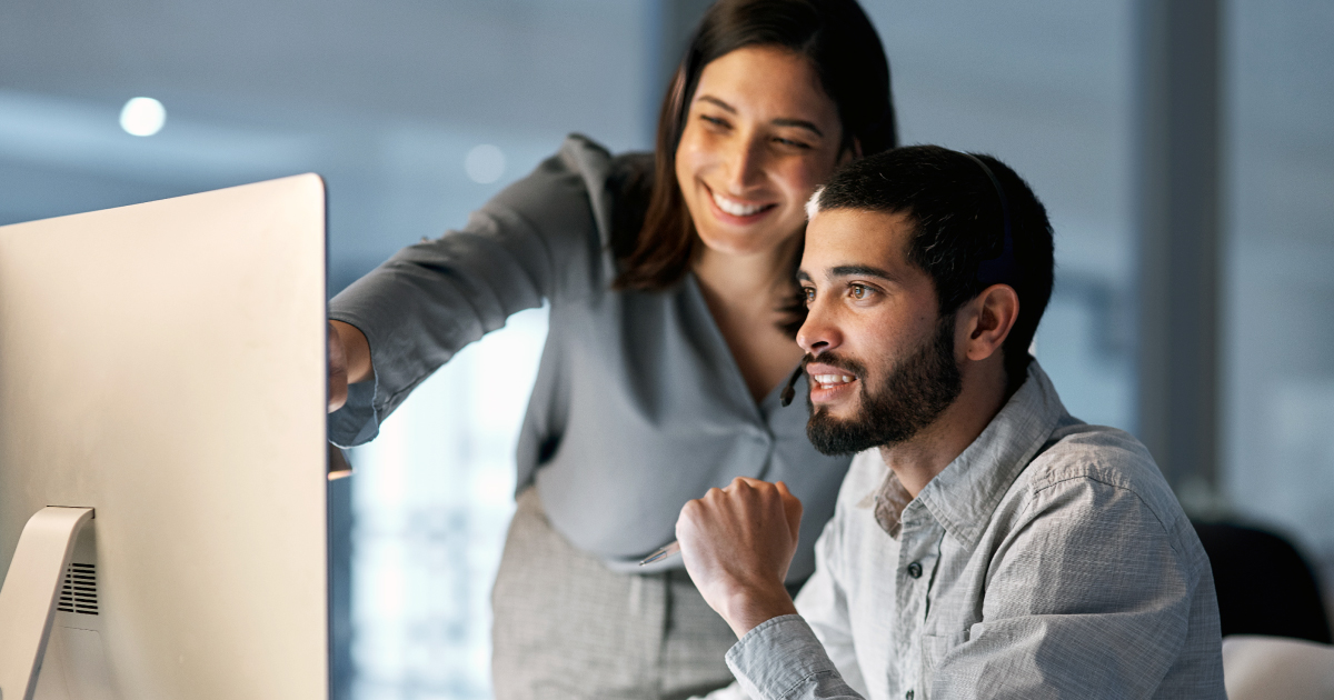 Two professionals reviewing data on a computer screen, representing automated underwriting and compliance processes in payments.