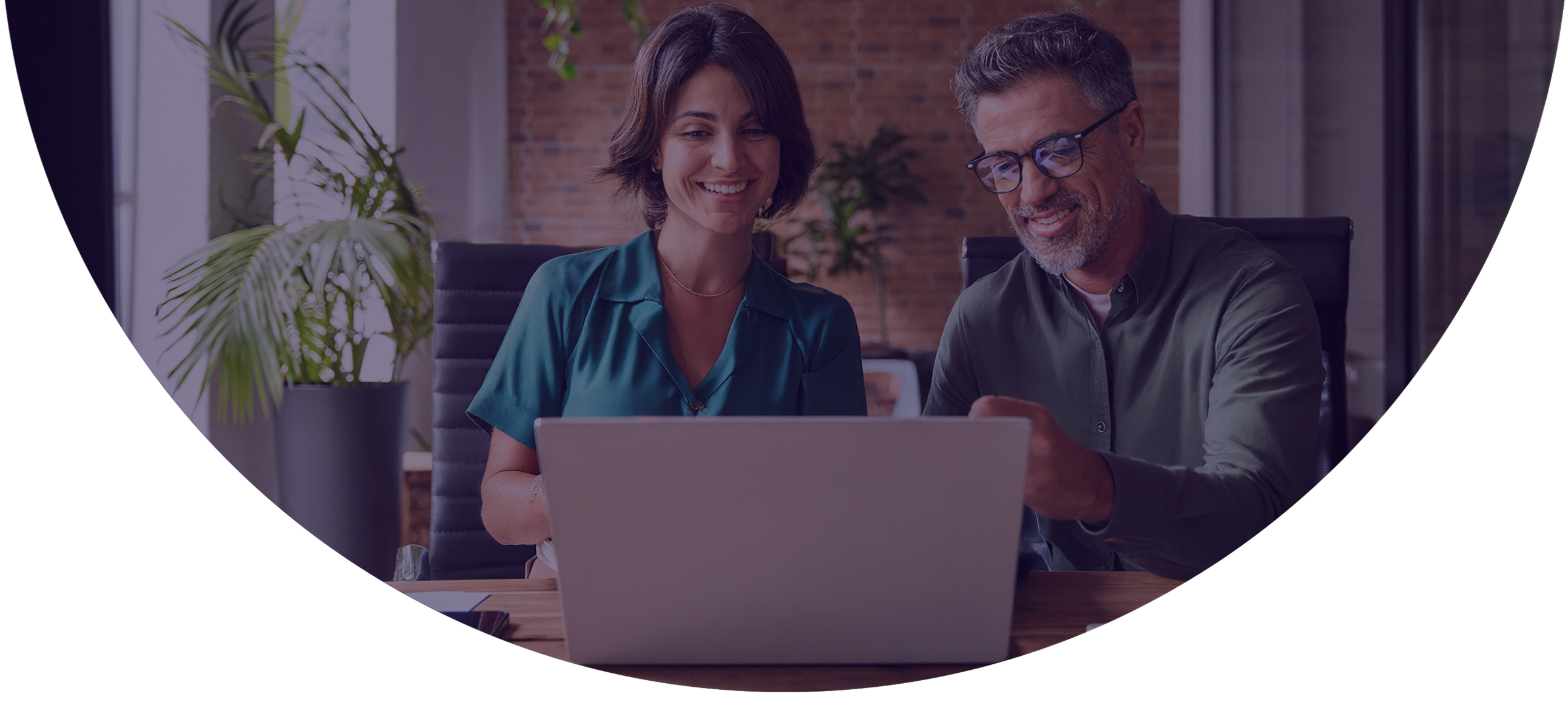 Two payments professionals smiling while reviewing merchant pipeline data together on a laptop using NMI Merchant Central's pipeline management tools.