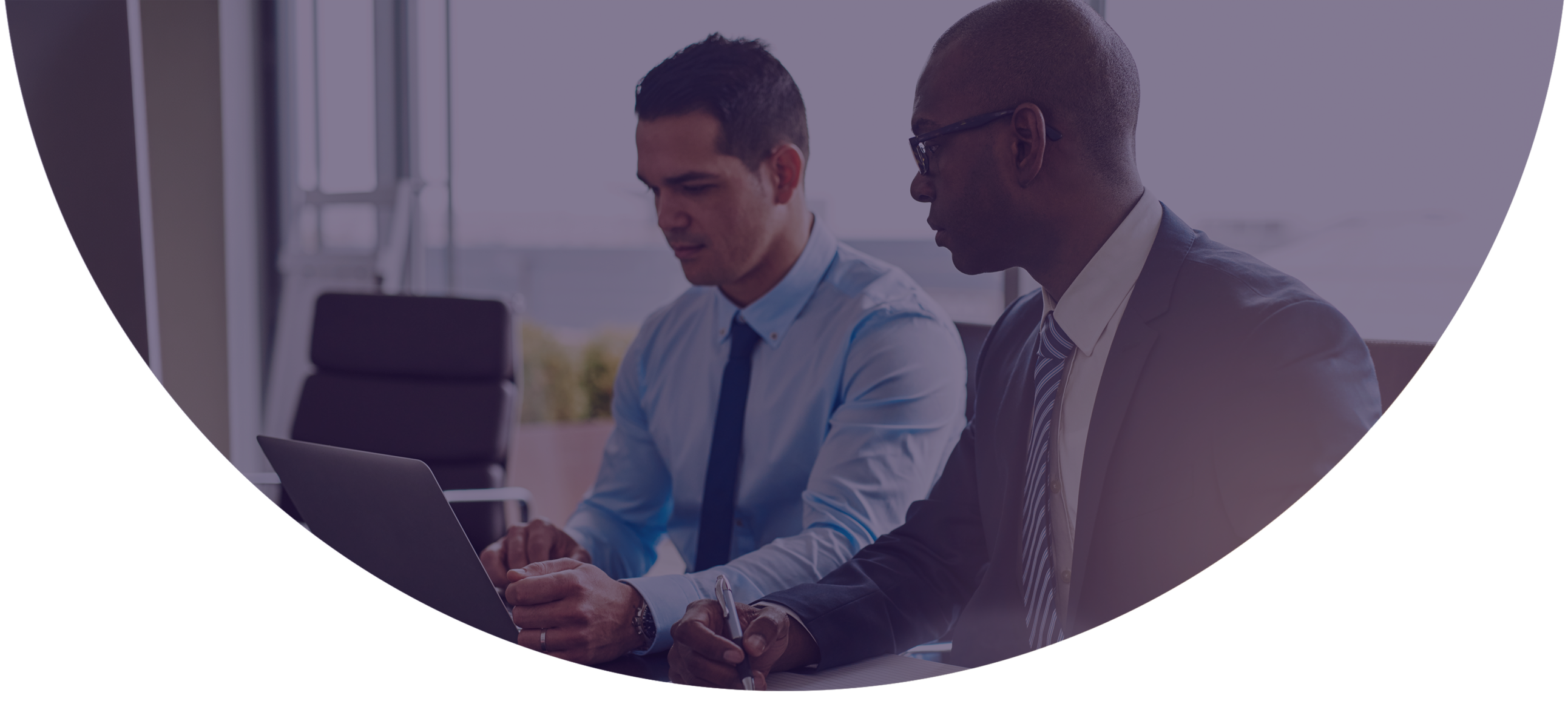 Two payments professionals reviewing merchant underwriting data together on a laptop using NMI Merchant Central's automated risk check and approval tools.