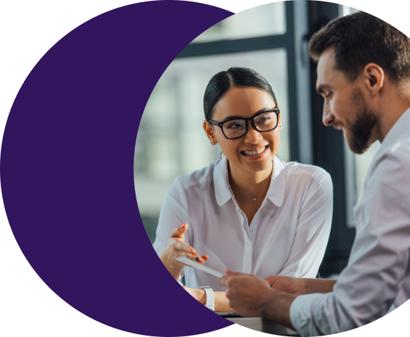 Two colleagues smiling and reviewing content on a screen together, representing a payments team using Merchant Central's role-based permissions and merchant visibility settings to control access and protect sensitive information.