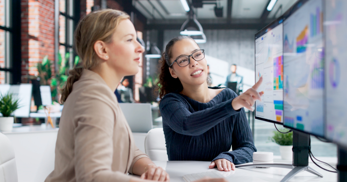 Two business professionals review underwriting data on a large screen in a modern office