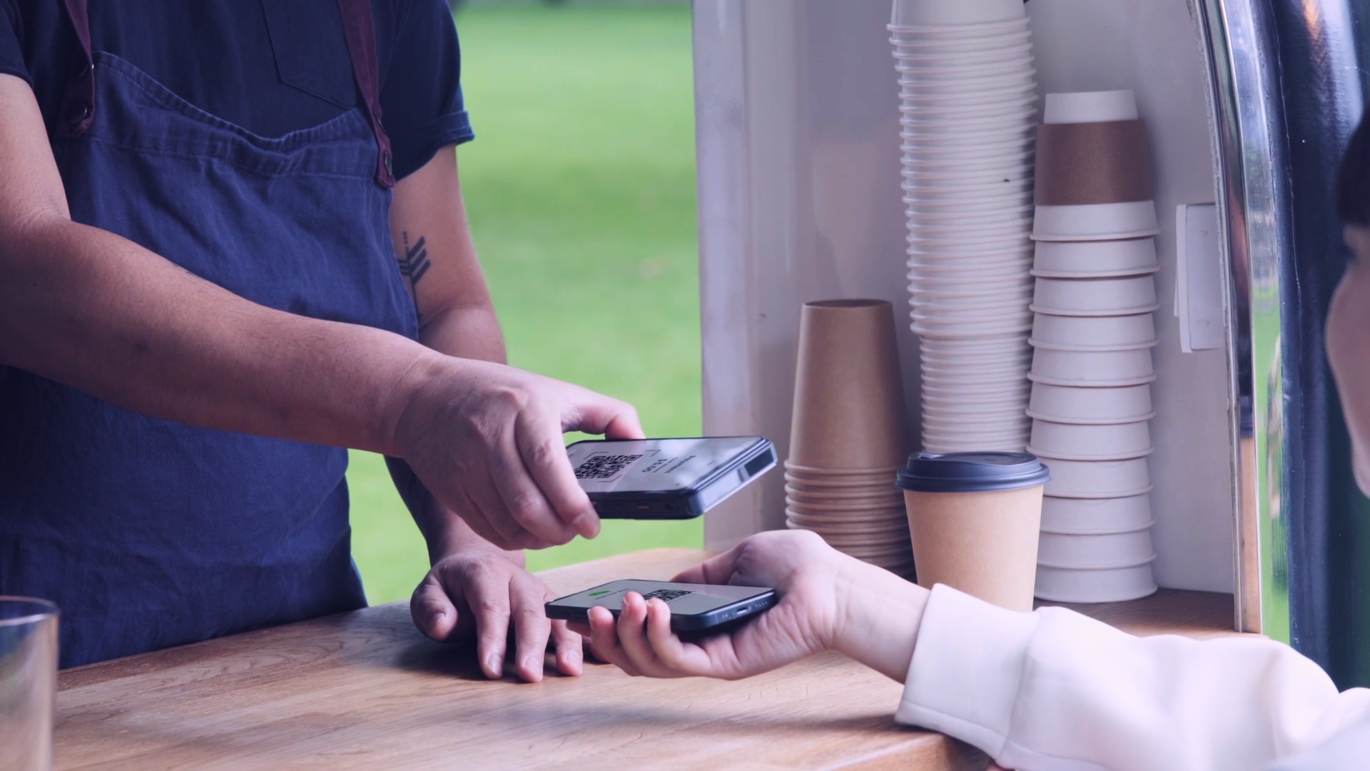 A mobile coffee cart takes a contactless payment from a customer's phone.