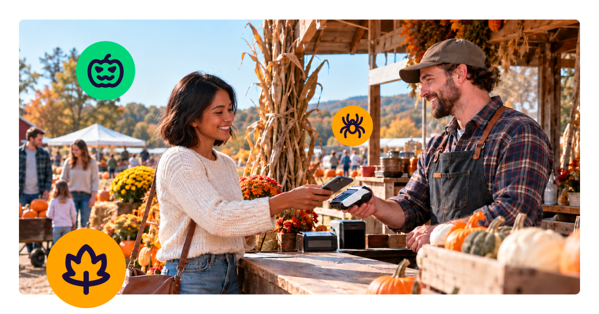 A customer taps her smartphone on a handheld payment terminal held by a smiling vendor at an outdoor pumpkin patch stand.